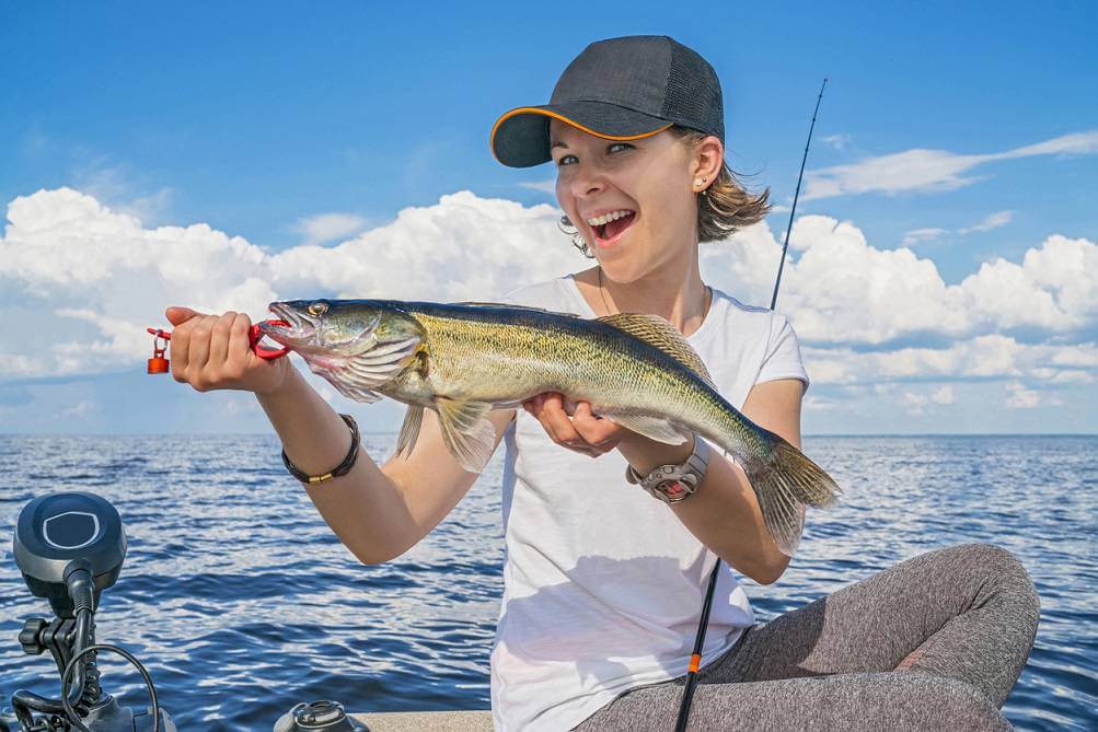 Happy fisher girl with walleye zander fish trophy at the boat